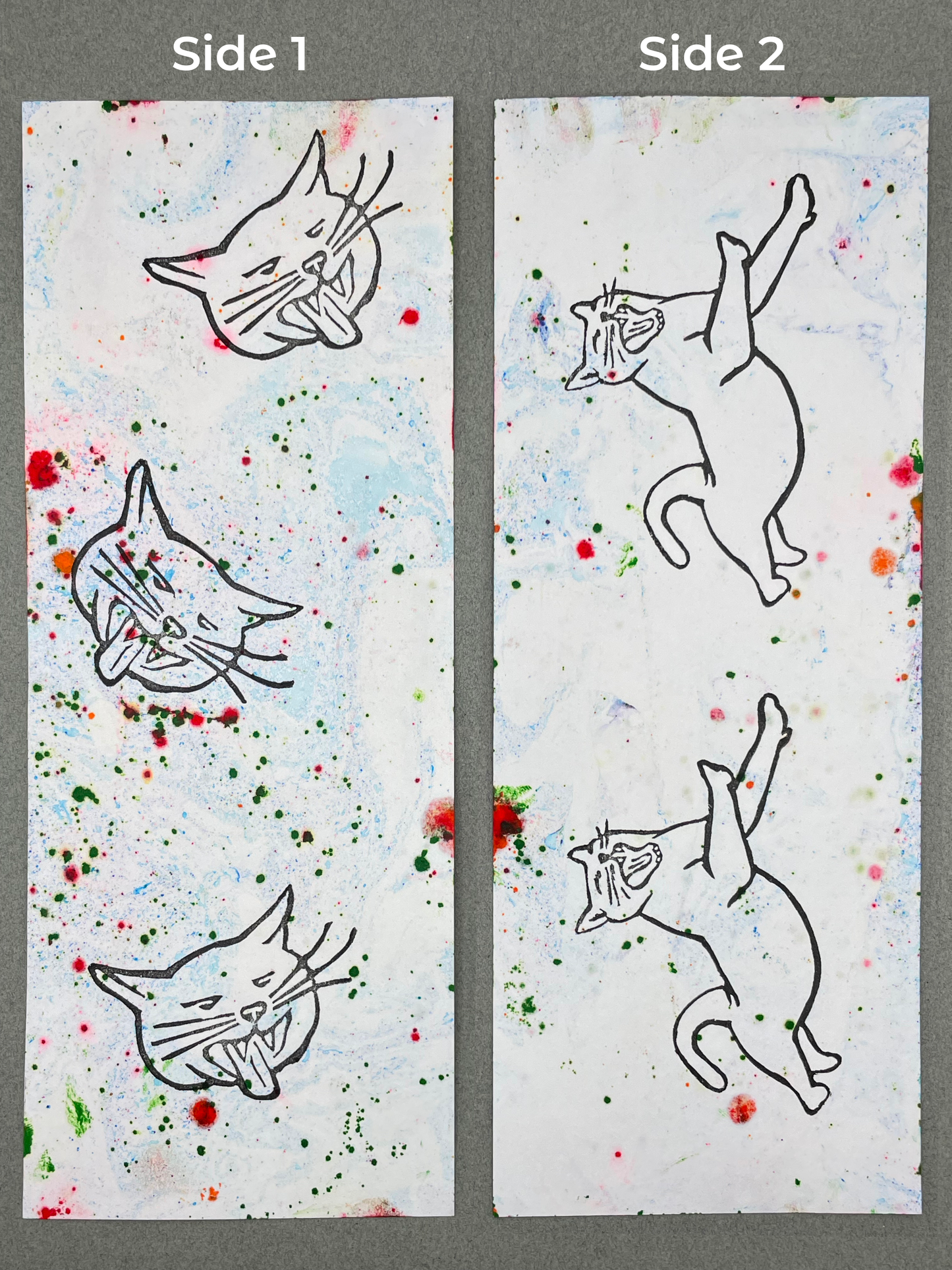 both sides of a bookmark are shown under their respective labels, which say "Side 1" and "Side 2". Side 1  shows light blue marbling with dots of various sizes of green and red and has three yawning cat faces on it. Side two has similar marbling and features two leaping cats