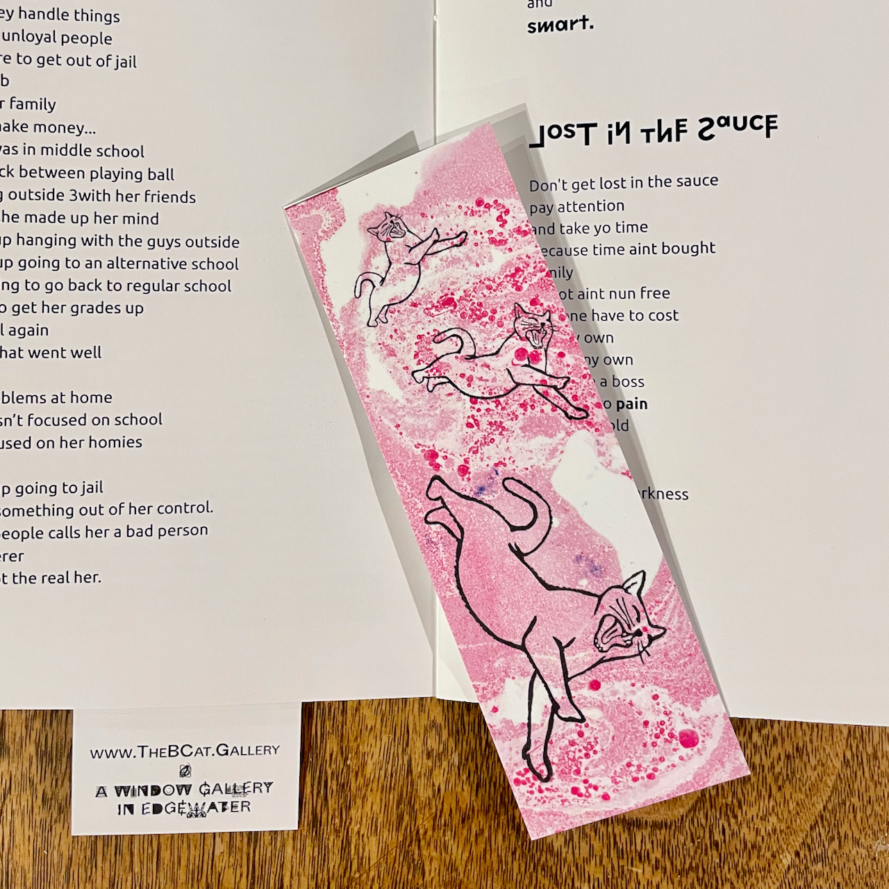 a bookmark of a cat leaping across a red, marbled background. The bookmark is on top of the Locked Achievements book