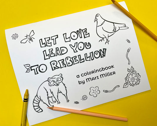 Coloring book laying on a yellow surface with crayons and colored pencils. Book cover says: Let Love Lead You To Rebellion a coloring book by Mari MIller. It's in black and white so it can be colored in and features stamps of a raccoon, pigeon, flowers, worms, and insects